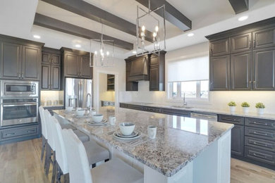 Transitional l-shaped light wood floor and beige floor eat-in kitchen photo in Montreal with a double-bowl sink, raised-panel cabinets, brown cabinets, granite countertops, white backsplash, ceramic backsplash, stainless steel appliances, two islands and multicolored countertops