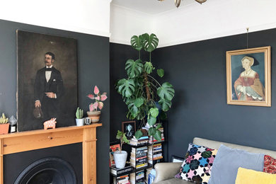 Photo of a traditional games room in London with black walls, light hardwood flooring, a standard fireplace and a wooden fireplace surround.
