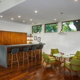 ダラスの中サイズのミッドセンチュリースタイルのおしゃれな着席型バー (フラットパネル扉のキャビネット、中間色木目調キャビネット、無垢フローリング、茶色い床、グレーのキッチンカウンター) の写真
