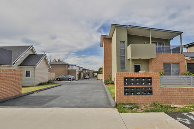 Photo of a mid-sized two-storey brick multi-coloured townhouse exterior in Sydney with a hip roof and a metal roof.
