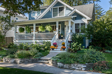 На фото: веранда на переднем дворе в классическом стиле с обшитым цоколем, мощением тротуарной плиткой, навесом и деревянными перилами с