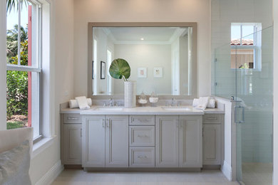 Example of a mid-sized transitional master white tile and glass tile porcelain tile and beige floor alcove shower design in Miami with recessed-panel cabinets, beige cabinets, white walls, an undermount sink, marble countertops and a hinged shower door