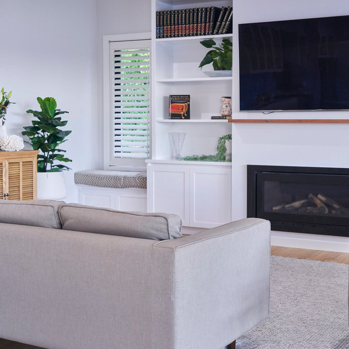 Inspiration for a small beach style open concept family room in Melbourne with a library, white walls, laminate floors, a standard fireplace, a plaster fireplace surround, a built-in media wall and br