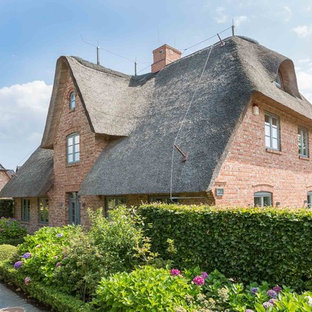 Rotes, Großes, Drei- oder mehrstöckiges Landhausstil Einfamilienhaus mit Backsteinfassade und Walmdach in Sonstige