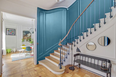 Cette image montre une grande entrée design avec un couloir, un mur bleu, parquet clair et un sol marron.