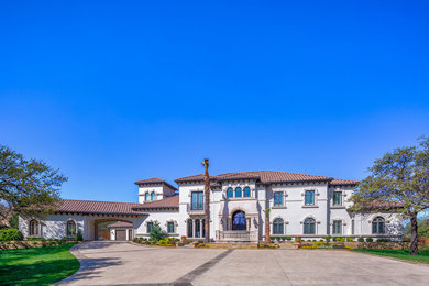 Photo of an expansive mediterranean two-storey stucco beige house exterior in Dallas with a tile roof.