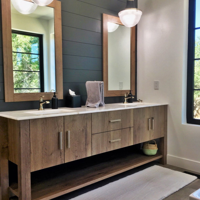 Natural wood finish double vanity with matching mirrors and a marble top in a luxury master bath.