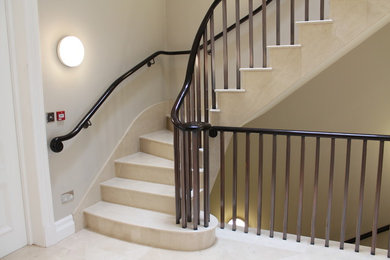 Design ideas for a large contemporary tile curved staircase in London with tile risers.