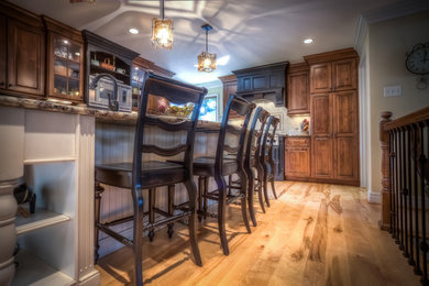 Inspiration for a mid-sized traditional single-wall eat-in kitchen in St Louis with light hardwood floors, with island, granite benchtops, stainless steel appliances, recessed-panel cabinets and medium wood cabinets.