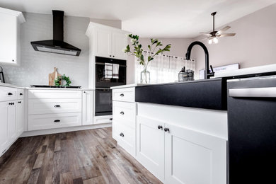 Eat-in kitchen - mid-sized cottage vinyl floor, brown floor and vaulted ceiling eat-in kitchen idea in Philadelphia with a farmhouse sink, shaker cabinets, white cabinets, quartz countertops, white backsplash, glass tile backsplash, black appliances, an island and white countertops