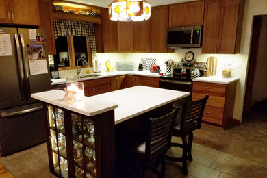 Mid-sized transitional l-shaped ceramic tile and yellow floor eat-in kitchen photo in Other with an undermount sink, shaker cabinets, medium tone wood cabinets, quartz countertops, stainless steel appliances, an island and white countertops