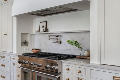 Example of a large transitional u-shaped limestone floor and beige floor enclosed kitchen design in Austin with beaded inset cabinets, white cabinets, quartzite countertops, beige backsplash, marble backsplash, stainless steel appliances, an island and beige countertops