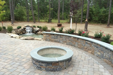 This is an example of a large traditional partial sun backyard brick landscaping in Richmond with a fire pit.