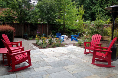 Example of a classic backyard stone patio design in Seattle