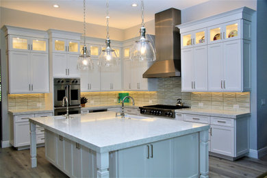 Beach style kitchen photo in Miami with shaker cabinets, stainless steel appliances and an island