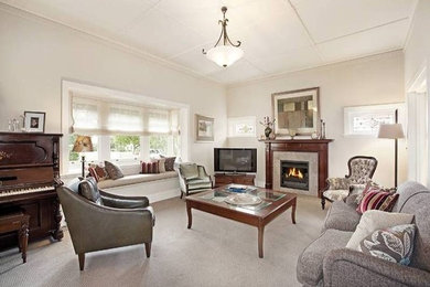 This is an example of a large eclectic formal enclosed living room in Melbourne with beige walls, carpet, a standard fireplace, a stone fireplace surround and a freestanding tv.