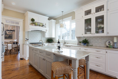 Example of a large classic u-shaped dark wood floor and brown floor eat-in kitchen design in Atlanta with white cabinets, quartzite countertops, stainless steel appliances, an island, an undermount sink, recessed-panel cabinets, white backsplash, subway tile backsplash and beige countertops