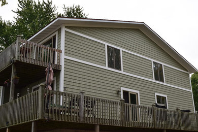 Large elegant green two-story wood exterior home photo in Chicago