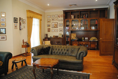 Modelo de sala de manualidades retro grande con paredes beige, suelo de madera en tonos medios y escritorio independiente
