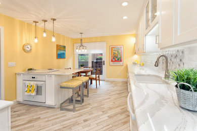 Example of a mid-sized transitional l-shaped linoleum floor and white floor eat-in kitchen design in St Louis with an undermount sink, recessed-panel cabinets, white cabinets, quartz countertops, white backsplash, ceramic backsplash, white appliances, an island and white countertops
