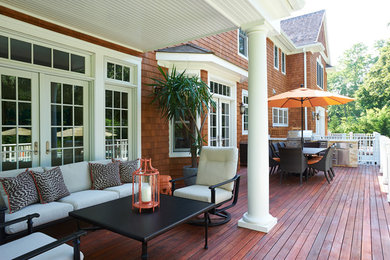 Large transitional backyard deck photo in New York with a roof extension