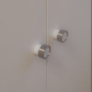 Cette photo montre un grand dressing tendance neutre avec un placard à porte plane, des portes de placard blanches, sol en stratifié, un sol marron et un plafond en papier peint.