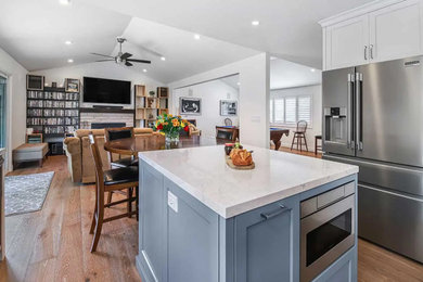 Open concept kitchen - large transitional l-shaped medium tone wood floor and beige floor open concept kitchen idea in San Francisco with an undermount sink, shaker cabinets, white cabinets, quartz countertops, subway tile backsplash, stainless steel appliances, an island, white countertops and gray backsplash