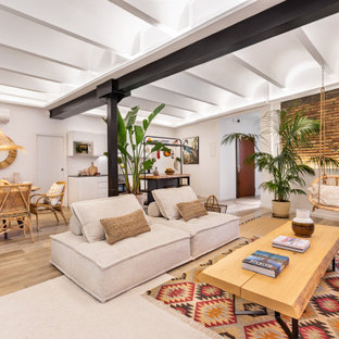 Imagen de sala de estar con barra de bar tipo loft y ladrillo, exótica, grande, sin chimenea, con paredes azules, suelo de madera clara, televisor independiente, suelo beige y ladrillo