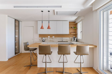 Ispirazione per una cucina ad U minimal con lavello a doppia vasca, ante lisce, ante bianche, paraspruzzi beige, paraspruzzi in lastra di pietra, pavimento in legno massello medio, penisola, pavimento marrone e top beige