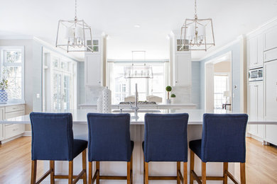 Beach style light wood floor and beige floor enclosed kitchen photo in New York with an undermount sink, shaker cabinets, white cabinets, paneled appliances, an island and white countertops