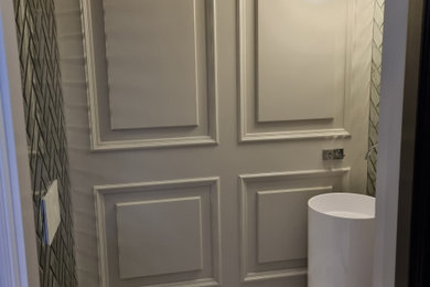 Photo of a small classic cloakroom in Other with a wall mounted toilet, mirror tiles, grey walls, marble flooring, a vessel sink, white floors, a feature wall and wainscoting.