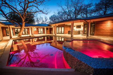 Inspiration for a mid-sized modern backyard stone and rectangular lap hot tub remodel in Dallas