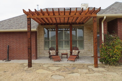 Mid-sized mountain style backyard stone patio photo in Oklahoma City with a pergola
