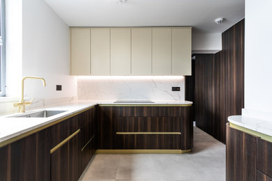 Inspiration for a mid-sized modern galley open plan kitchen in London with marble benchtops, white splashback, engineered quartz splashback, with island and beige benchtop.