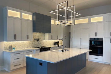 Inspiration for a large classic l-shaped kitchen/diner in Miami with a submerged sink, recessed-panel cabinets, white cabinets, engineered stone countertops, black appliances, light hardwood flooring and an island.