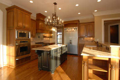 Eat-in kitchen - large craftsman u-shaped medium tone wood floor eat-in kitchen idea in Nashville with an undermount sink, raised-panel cabinets, medium tone wood cabinets, granite countertops, beige backsplash, stainless steel appliances and an island