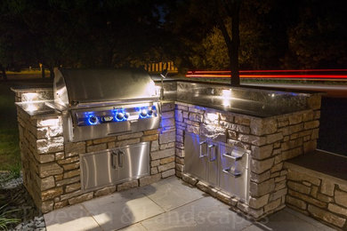 This is an example of a small traditional backyard patio in Minneapolis with an outdoor kitchen, natural stone pavers and no cover.