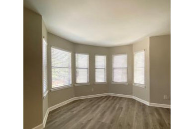Family room - mid-sized contemporary open concept medium tone wood floor and gray floor family room idea in Charlotte with gray walls and no fireplace