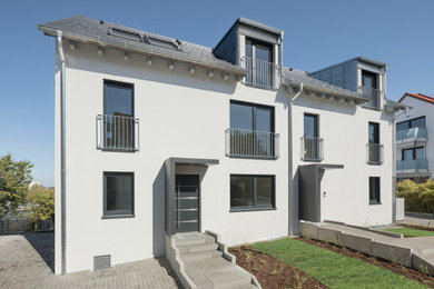 Ejemplo de fachada de casa pareada blanca y gris moderna con revestimiento de estuco, tejado a dos aguas y tejado de teja de barro