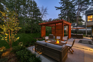 Photo of a mid-sized modern partial sun backyard stone landscaping in Milwaukee with a pergola.