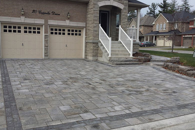 This is an example of a mid-sized modern front yard brick driveway in Toronto.