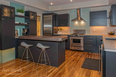 Inspiration for a contemporary medium tone wood floor kitchen remodel in St Louis with an undermount sink, flat-panel cabinets, black cabinets, quartz countertops, blue backsplash, glass tile backsplash and stainless steel appliances