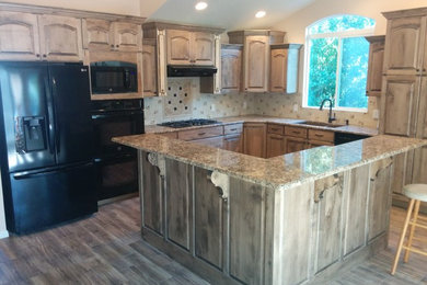 Large elegant l-shaped medium tone wood floor and brown floor open concept kitchen photo in Salt Lake City with an undermount sink, raised-panel cabinets, medium tone wood cabinets, granite countertops, beige backsplash, cement tile backsplash, black appliances and an island