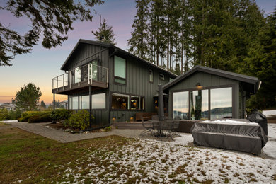 Large trendy green two-story wood and board and batten exterior home photo in Seattle with a metal roof and a gray roof