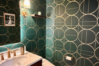 Inspiration for a small transitional medium tone wood floor, brown floor and wallpaper powder room remodel in Philadelphia with furniture-like cabinets, brown cabinets, a bidet, green walls, an undermount sink, quartz countertops, multicolored countertops and a freestanding vanity