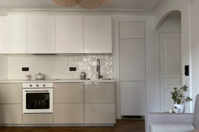 Idées déco pour une petite cuisine ouverte linéaire et beige et blanche avec un évier 1 bac, un placard à porte plane, des portes de placard beiges, un plan de travail en stratifié, une crédence beige, une crédence en céramique, un électroménager blanc, un sol en bois brun, îlot, un sol marron et un plan de travail beige.