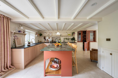 Photo of a classic l-shaped kitchen in Cornwall with a submerged sink, shaker cabinets, pink cabinets, an island, grey floors and black worktops.