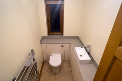 Small contemporary cloakroom in Cardiff with flat-panel cabinets, beige cabinets, a one-piece toilet, beige walls, travertine flooring, a vessel sink, solid surface worktops, beige floors, green worktops and a built in vanity unit.