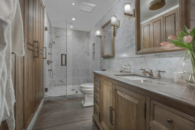 Mid-sized eclectic 3/4 bathroom in New York with furniture-like cabinets, light wood cabinets, an alcove shower, a two-piece toilet, brown tile, stone tile, white walls, limestone floors, an undermount sink and limestone benchtops.