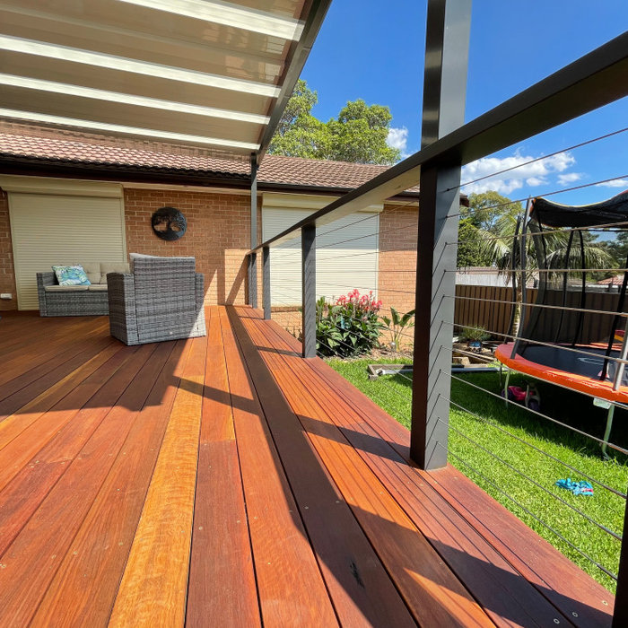 This is an example of a large modern backyard and ground level deck in Sydney with a pergola.